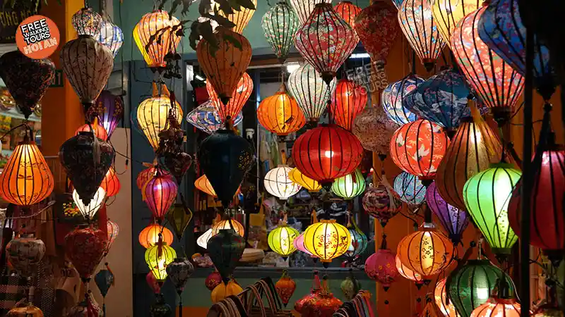 Colourful silk lanterns hanging in a lantern shop in Hoi An Ancient Town, glowing in warm evening light.