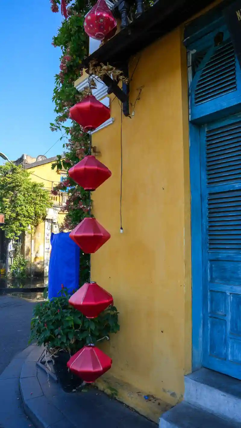 Red silk lanterns against a yellow wall in Hoi An