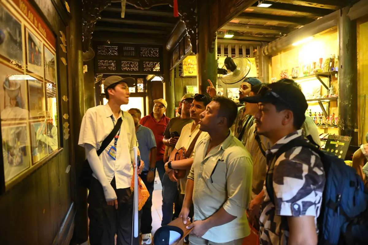 Local guide explaining the interior of a historic merchant house during a Hoi An walking tour.